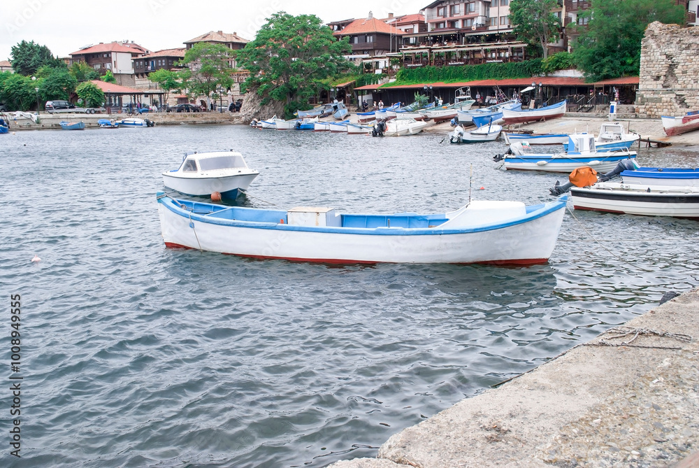 Fototapeta premium Boats mooring on sea in Nessebar, Bulgaria. Summer landscape with moored woods boat at quay by blue sky