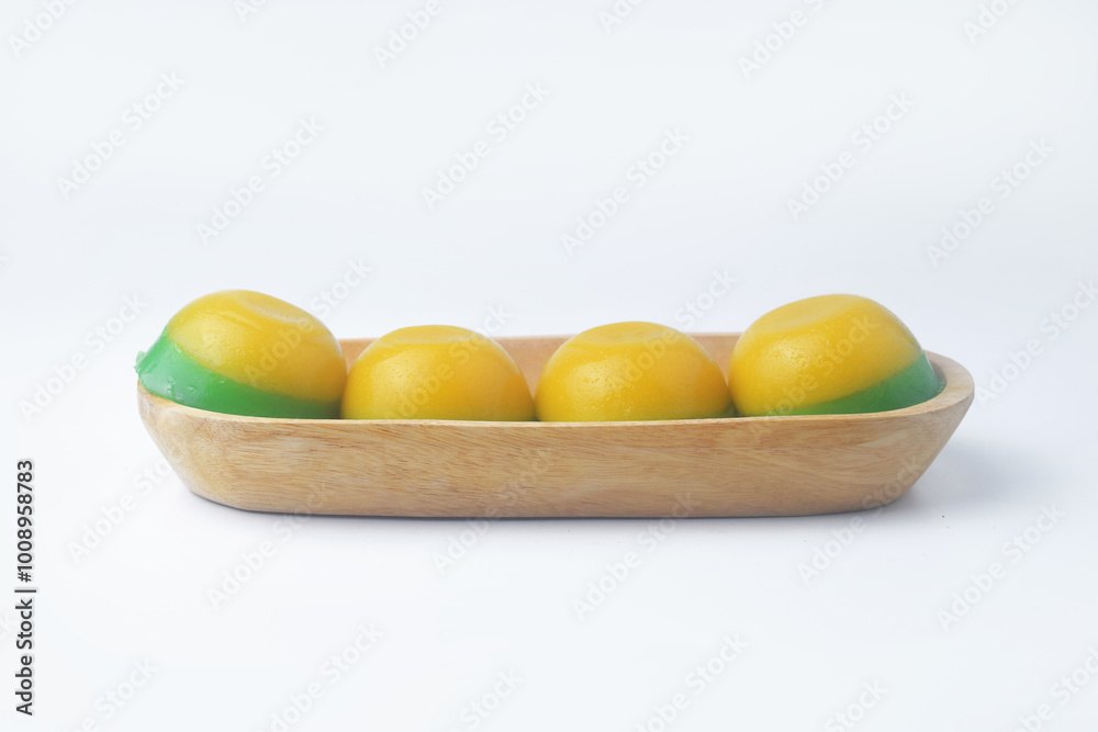 Round yellow green layered cake in a wooden bowl is an Indonesian food Round yellow green layered cake in a wooden bowl is an Indonesian food