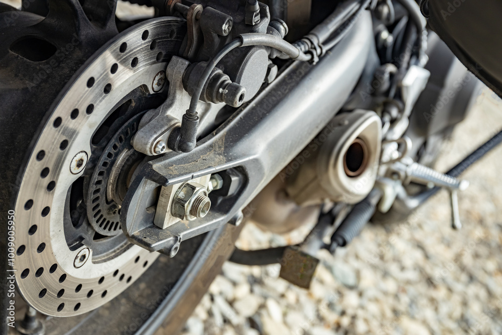 The rear of a motorcycle with chain drive to the rear wheel. The rear of a motorcycle with chain drive to the rear wheel.