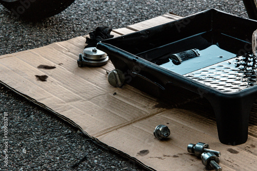 a pallet of used engine oil on a cardboard mat next to the motorcycle