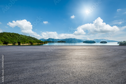 Fototapeta Naklejka Na Ścianę i Meble -  Asphalt road square and clear lake with green mountain nature landscape under blue sky. Car background.