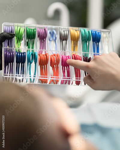 Colorful orthodontic ligatures in hands of patient in dental office. Set of brightly colored rubber bands for braces. Front view. Copy Space. photo