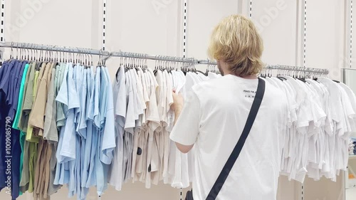 young man choosing clothes in a shopping mall. clothes hangers