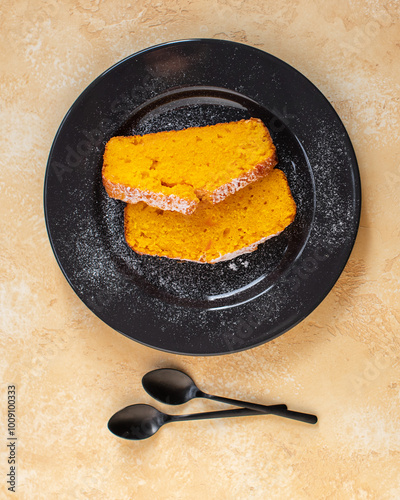 Fresh baked homemade pumpkin pie on a black ceramic plate. Bright yellow background. Close up. Top view.