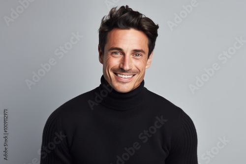 Portrait of a smiling man in his 30s wearing a classic turtleneck sweater while standing against white background
