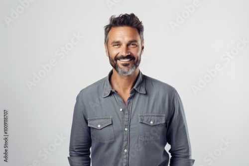 Portrait of a content man in his 40s sporting a versatile denim shirt in front of white background