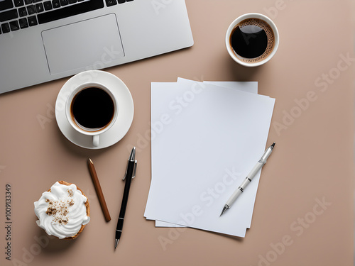 Draufsicht auf einen Schreibtisch mit Kaffee, einem Cupcake, Laptop, Stiften und leerem Papier