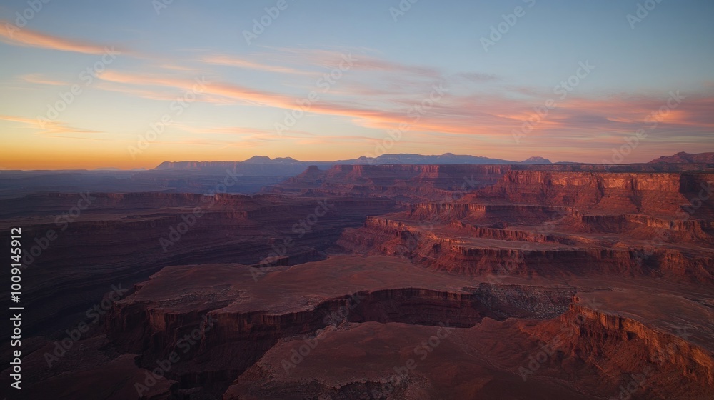 A panoramic view of a canyon at sunset with a hazy pink sky. A panoramic view of a canyon at sunset with a hazy pink sky.