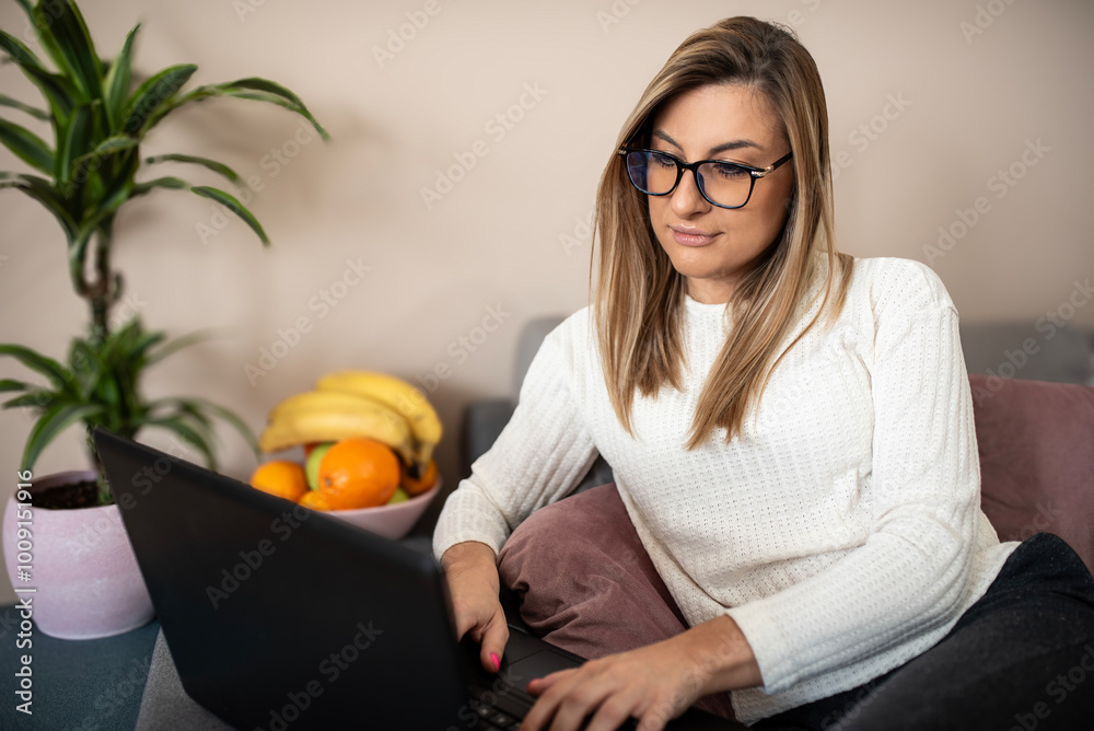 Beautiful woman works at home, using laptop, typing messages. Business woman casually looks, watch movies and doing homework on computer at home