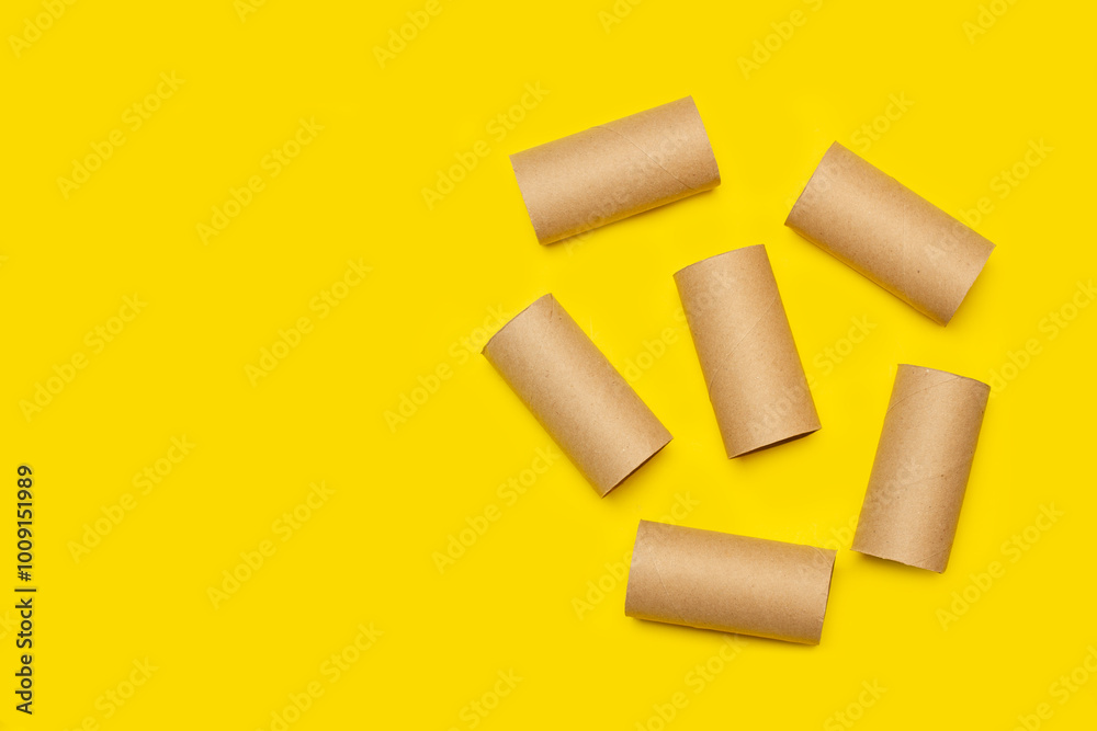 Cardboard toilet paper rolls without paper on a yellow background with copy space