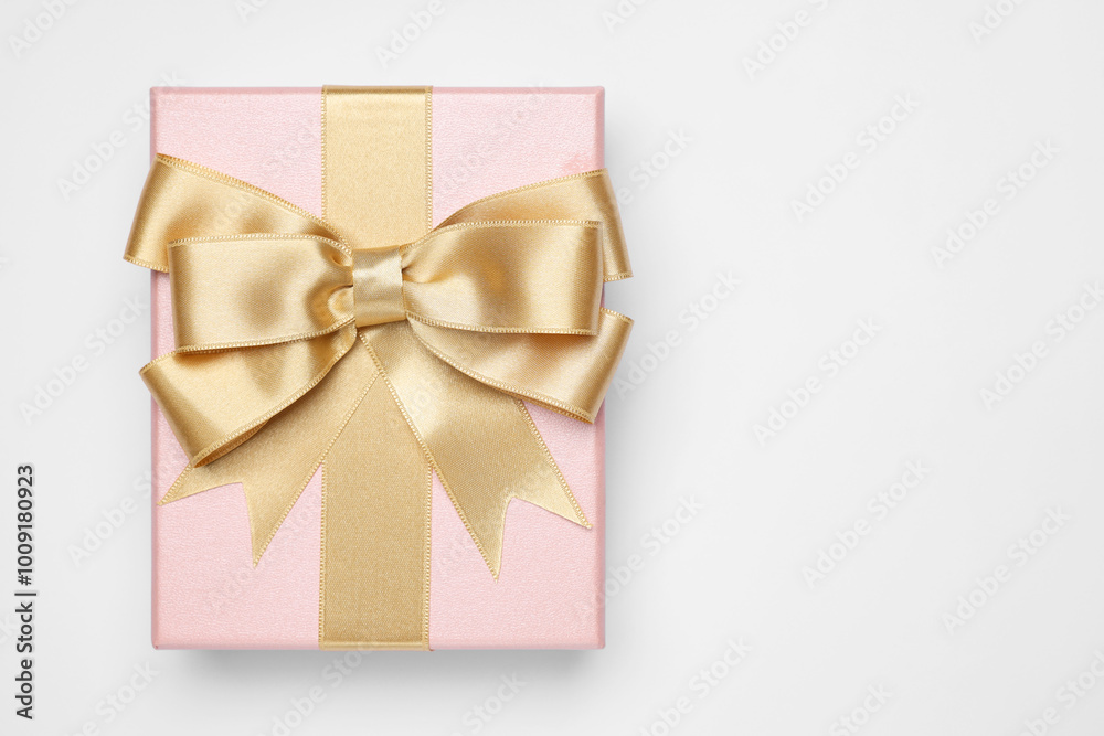 Gift box with golden bow on light grey background, top view. Space for text Gift box with golden bow on light grey background, top view. Space for text