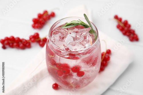 Refreshing water with red currants and rosemary in glass on white tiled table, closeup