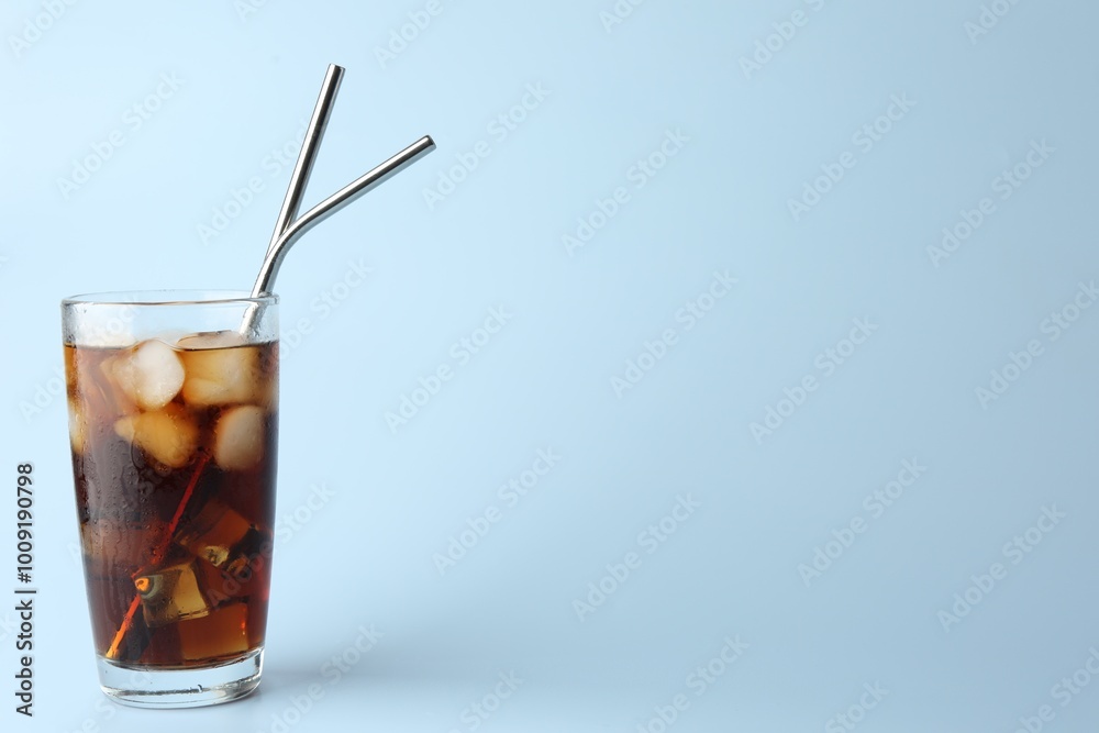 Tasty refreshing drink with straws in glass on light blue background, space for text Tasty refreshing drink with straws in glass on light blue background, space for text