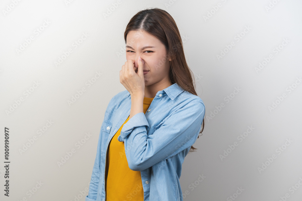 Portrait of pretty brunette hair, disgust smell bad strong asian young woman, girl hand squeezing, covering nose with fingers, expression face disgusting, dislike odor isolated on white background. Portrait of pretty brunette hair, disgust smell bad strong asian young woman, girl hand squeezing, covering nose with fingers, expression face disgusting, dislike odor isolated on white background.