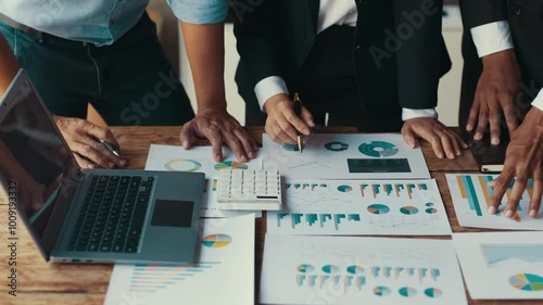 Business team collaborating on financial data analysis at a wooden table, showcasing teamwork and strategic planning