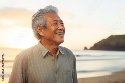 Portrait of a blissful asian elderly man in his 90s donning a trendy cropped top isolated in beautiful beach sunset