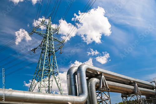 close up of pipeline and power line, blue sky and clouds in the background
