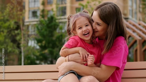 a child and his mother are talking on a park bench in the summer, having fun together, a happy childhood, mom and daughter