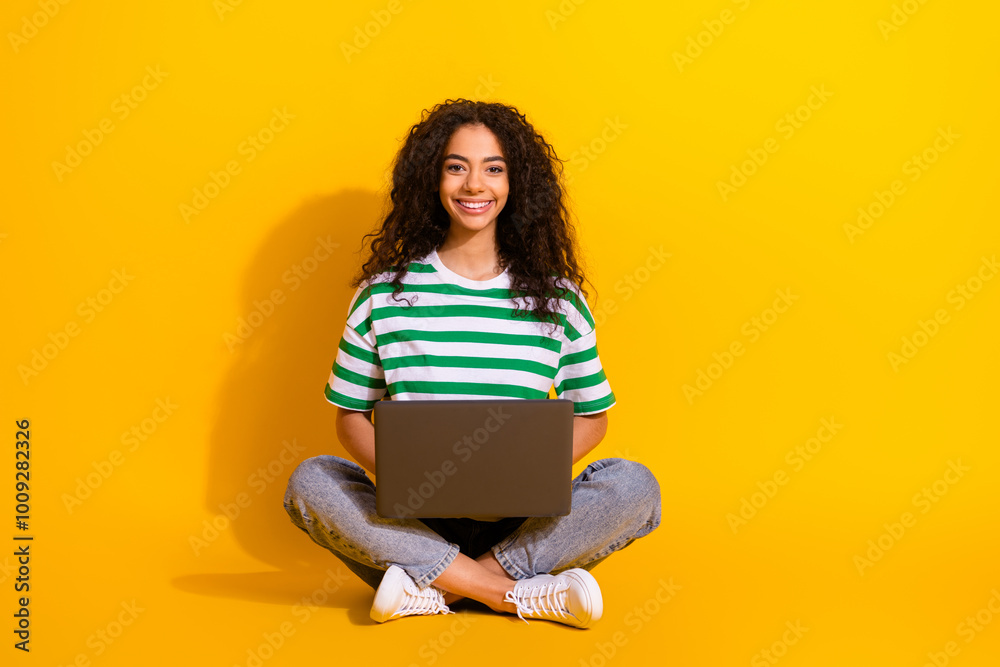 Full size photo of pretty young girl use laptop empty space wear striped t-shirt isolated on yellow color background