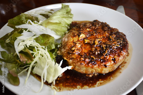 Japanese hambagu is a hamburger steak made from ground beef or pork, mixed with onions and breadcrumbs, then pan-fried. It's served with a rich sauce, typically alongside rice or vegetables. photo