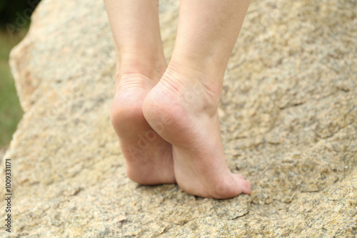 Woman standing barefoot on rock outdoors, closeup