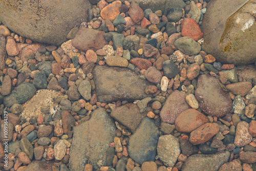 A shallow stream with rocks and pebbles at the bottom. The water is crystal clear, allowing you to see the stones and pebble clearly. Stones and pebbls vary in size and colour.  photo