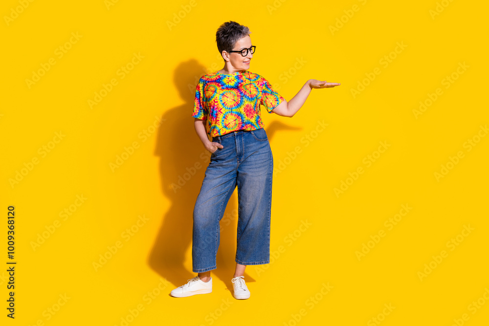 Photo of charming cheerful retired woman wear stylish clothes presenting empty space isolated on yellow color background Photo of charming cheerful retired woman wear stylish clothes presenting empty space isolated on yellow color background