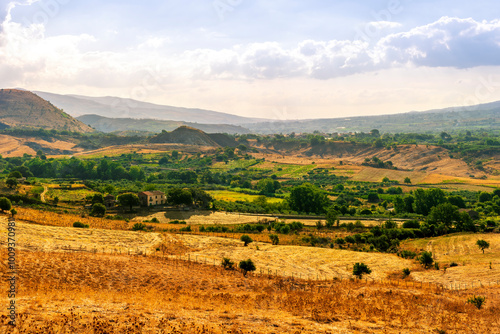 panoramic farmland view of yellow field with sceniv valley , mountains and amazing cloudt sunset photo