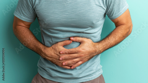 A man expresses discomfort by holding his stomach. This image conveys feelings of pain and concern, set against a calming blue background, ideal for health-related topics.