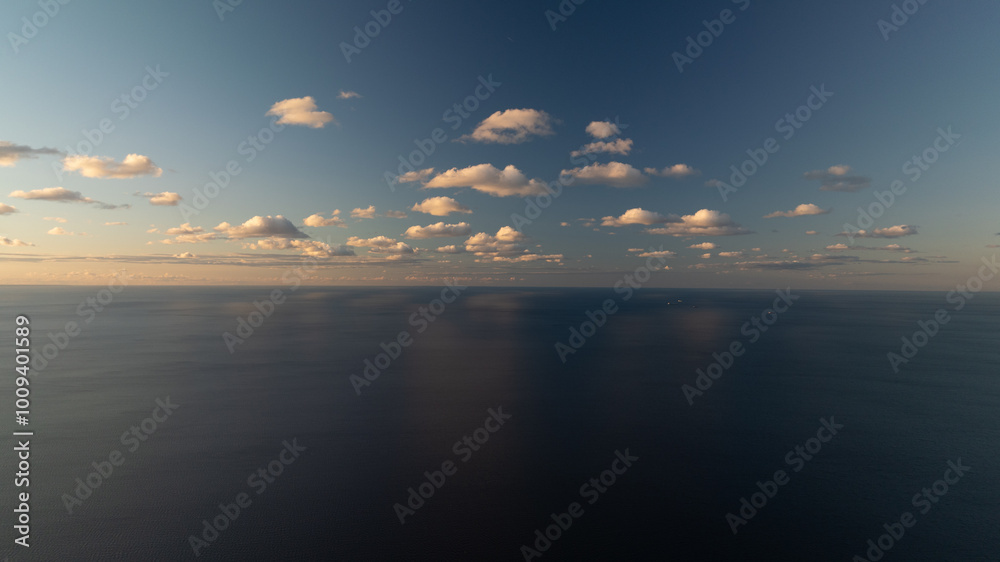 Fototapeta premium Under a blue sky dotted with clouds, a sizable expanse of water houses a solitary boat