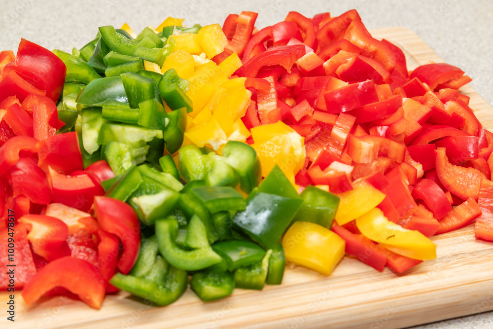 Wooden cutting board with freshly cut green, yellow, red paprika, peppers on the kitchen countertop. Close-up view. Healthy food cooking, home made healthy dinner. Fresh vegetables Wooden cutting board with freshly cut green, yellow, red paprika, peppers on the kitchen countertop. Close-up view. Healthy food cooking, home made healthy dinner. Fresh vegetables