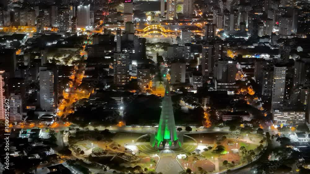 Vista aérea noturna da catedral de Maringá, Paraná, com a cidade ao fundo.
