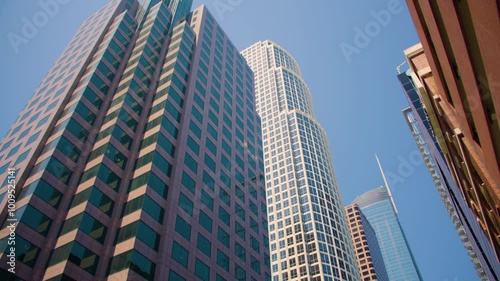 Tilt down shot from the tops of hi-rise buildings set against clear blue sky and to the street of metropolitan downtown. Skyscrapers in a cityscape with bright blue sky. Los Angeles on a sunny day.