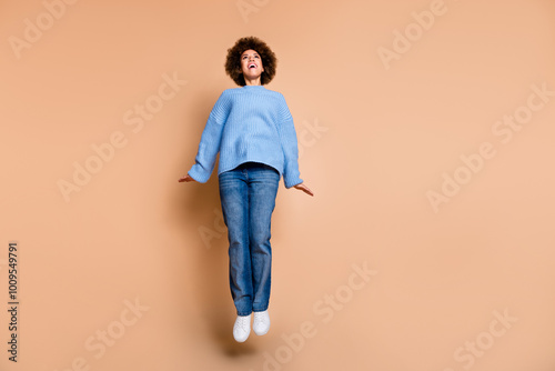 Full size photo of good mood girl dressed knit sweater jeans jumping look at proposition empty space isolated on pastel color background photo