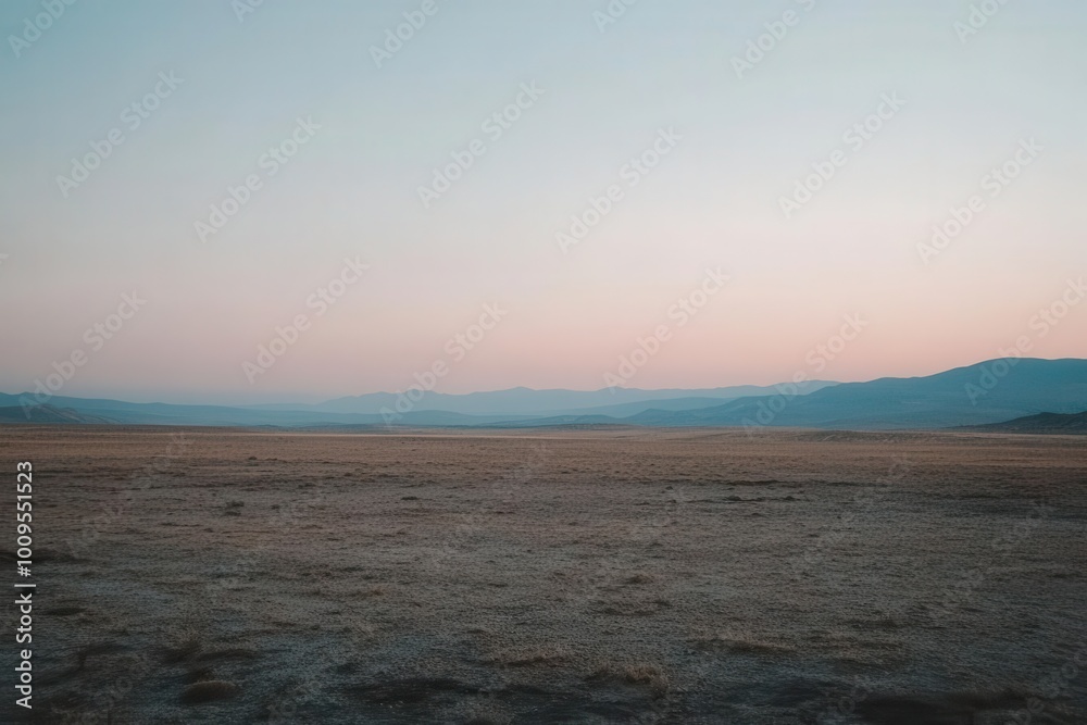 Fototapeta premium A serene landscape at dusk, featuring vast plains and distant mountains under a pastel sky.