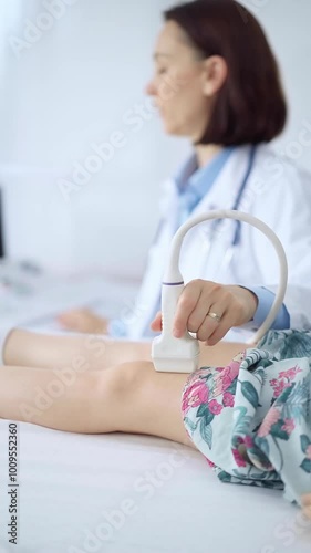 Doctor and kid patient. Orthopedist performing ultrasound examination on a child's knee in a clinic. Medicine and health care photo