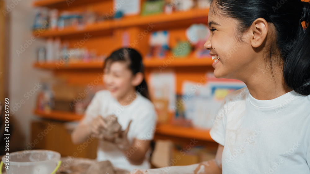 Young happy caucasian girl modeling cup with friend at pottery workshop. Smart asian girl smash dough while attend in art lesson when friend doing creative activity. Blurred background. Edification. Young happy caucasian girl modeling cup with friend at pottery workshop. Smart asian girl smash dough while attend in art lesson when friend doing creative activity. Blurred background. Edification.