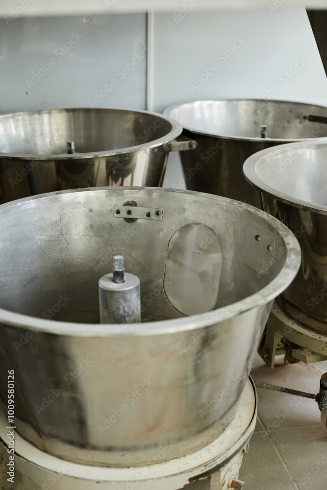 Vertical shot of metal reservoirs stored at factory as removable parts of industrial centrifuge or mixing tank for powders at pharmaceutical manufacturing plant, copy space Vertical shot of metal reservoirs stored at factory as removable parts of industrial centrifuge or mixing tank for powders at pharmaceutical manufacturing plant, copy space