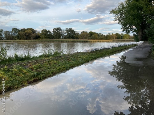 Flooded fields and asphalt road with sandbag barriers along the Iłownica River during flood in September 2024 in Poland in Czechowice Dziedzice. Topics: natural disaster, river alert status, nature photo