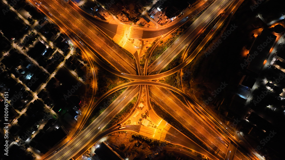 Obraz premium Aerial drone long exposure night shot of highway multilevel junction highway with light traffic leaving car headlights white and red trails
