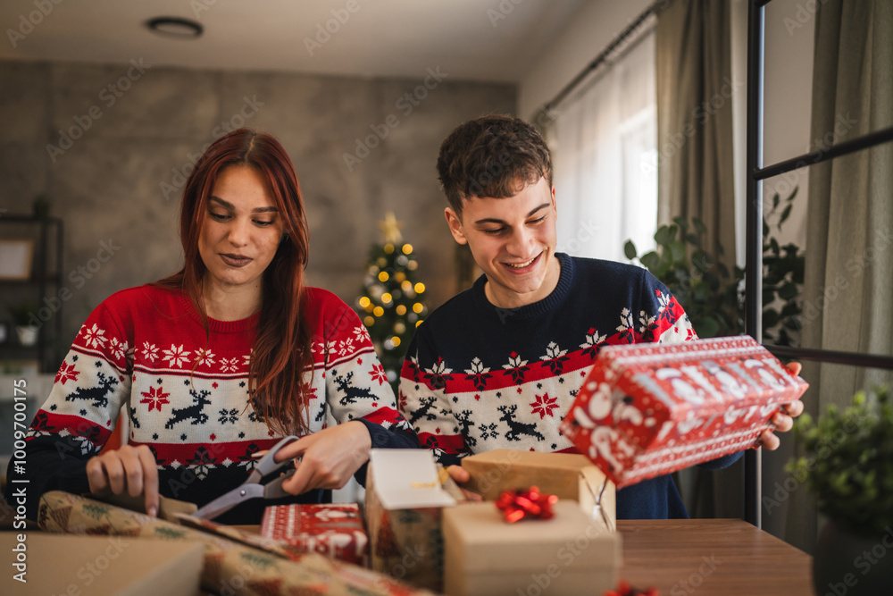 Fototapeta premium Adult young couple wrap Christmas gift with festive decorations