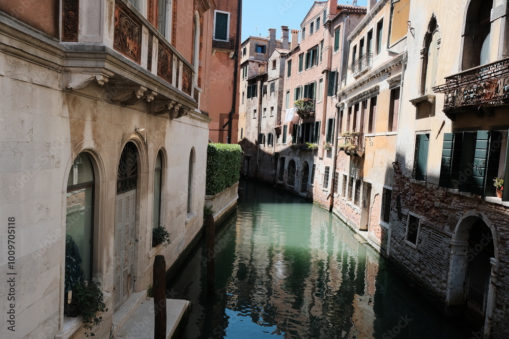 A small, enchanting canal is located between two buildings in Venice