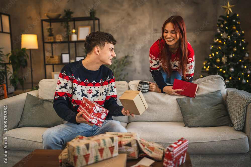 Obraz premium Girlfriend talk to her boyfriend while he wrap Christmas gift at home