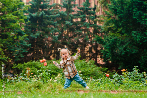 Portrait of a cheerful toddler girl Caucasian child in a shirt in a park in summer.