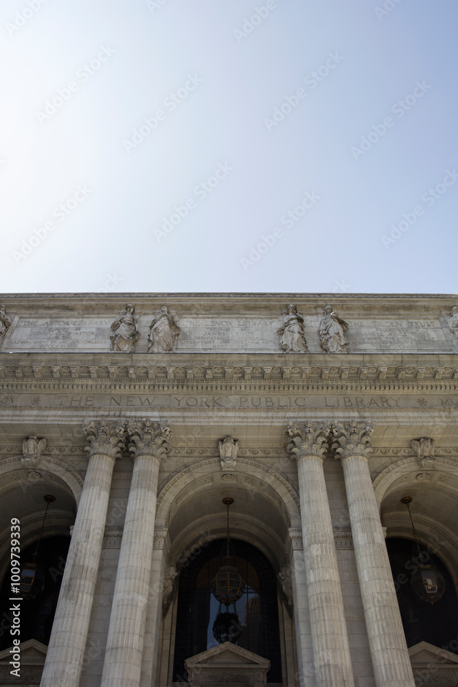 Fototapeta premium Striking façade of the New York Public Library, featuring towering columns and elegant sculptures amidst the hustle of the bustling city
