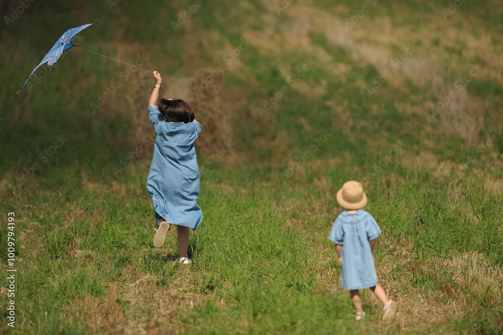 mother and child running across the field with a kite