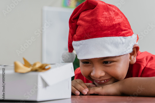 Young boy in Santa hat excitedly looking at Christmas gift photo