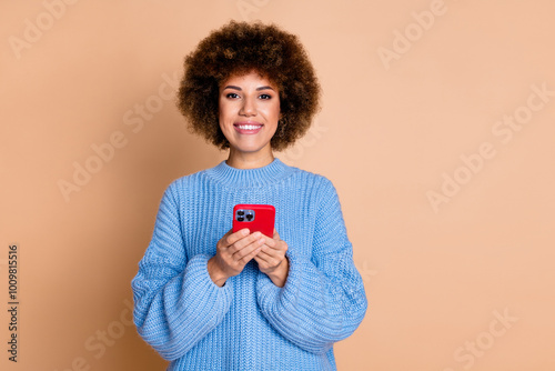 Photo of good mood positive girl with perming coiffure dressed blue knit sweater hold smartphone isolated on pastel color background