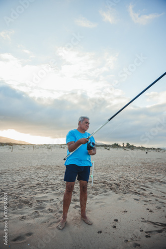 Elderly fisherman casting line at sunset on Valencia beach photo