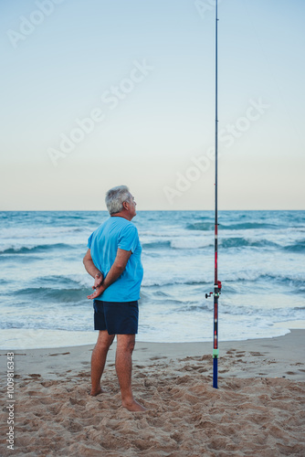 Senior fisherman fishing at twilight on Valencia beach photo